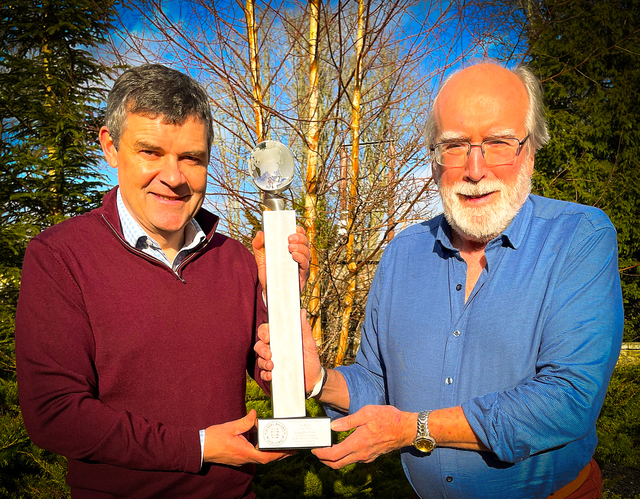 John Lamond, Author, Whisky Expert, and Senior Judge of the Global Whisky Challenge (right), presents the Global Whisky Challenge 2024 “Best of Show” 1st Place Trophy to Euan Mitchell, Managing Director of Arran Whisky for Lagg Distillery’s Single Malt Scotch Whisky-Corriecravie Edition, Sherry Cask Finish. 